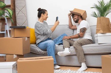 Couple relaxing and taking photos with cardboard boxes on moving day in Dubai.