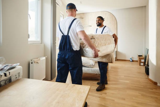 Two professional movers carrying a wrapped sofa during a home relocation in Dubai.
